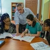 girl pointing out something in book to others